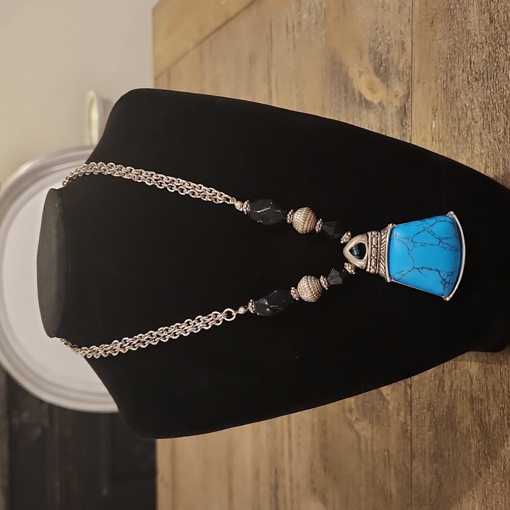 Silver tone necklace with turquoise color and black beads.